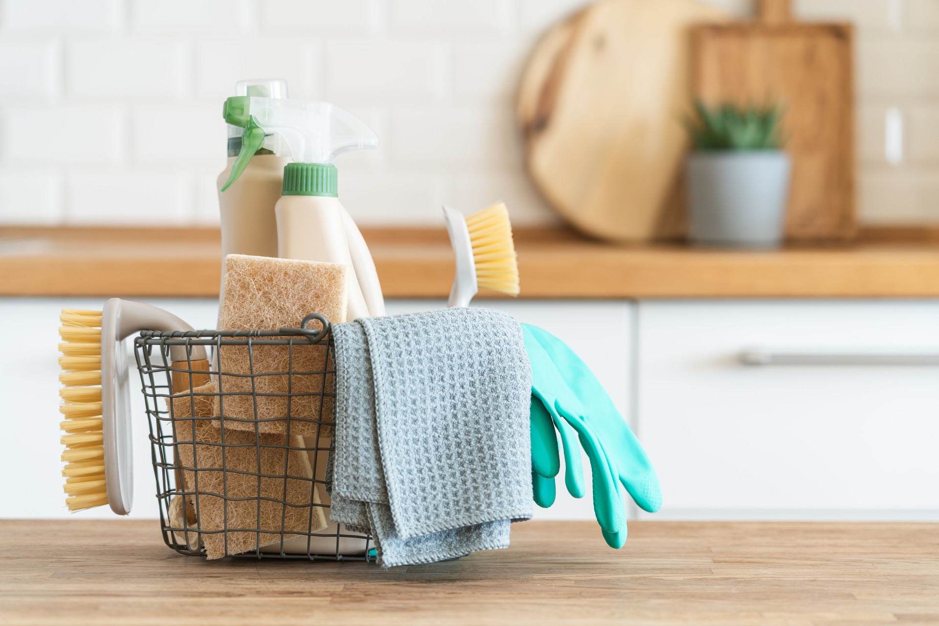 Cesta con cepillos, trapos, esponjas naturales y productos de limpieza.